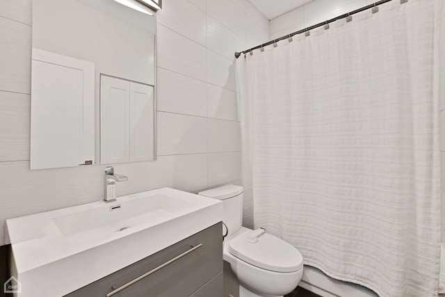 bathroom featuring vanity, curtained shower, toilet, and tile walls