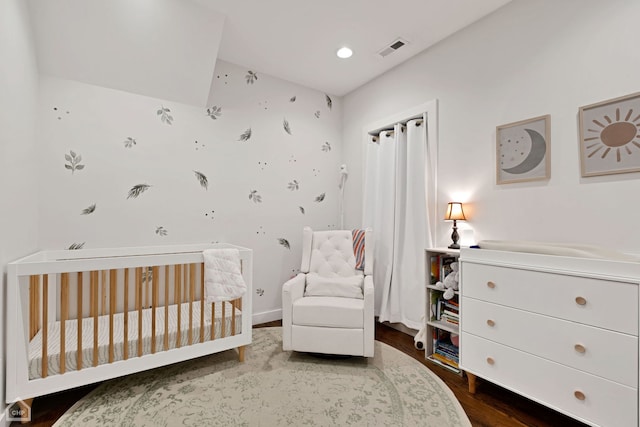 bedroom featuring hardwood / wood-style flooring and a nursery area