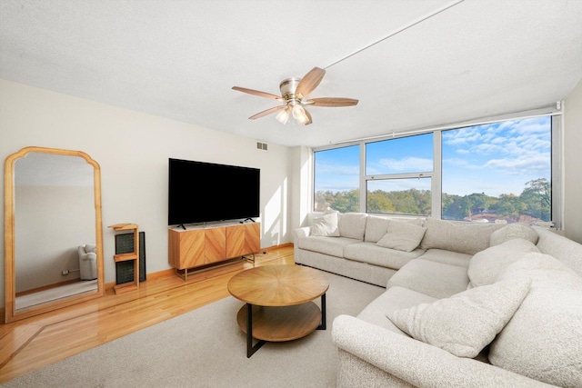 living room with hardwood / wood-style floors, ceiling fan, and a textured ceiling