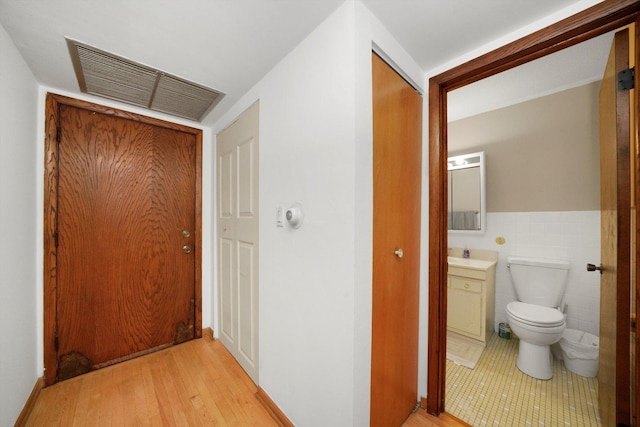 corridor featuring light hardwood / wood-style flooring and tile walls