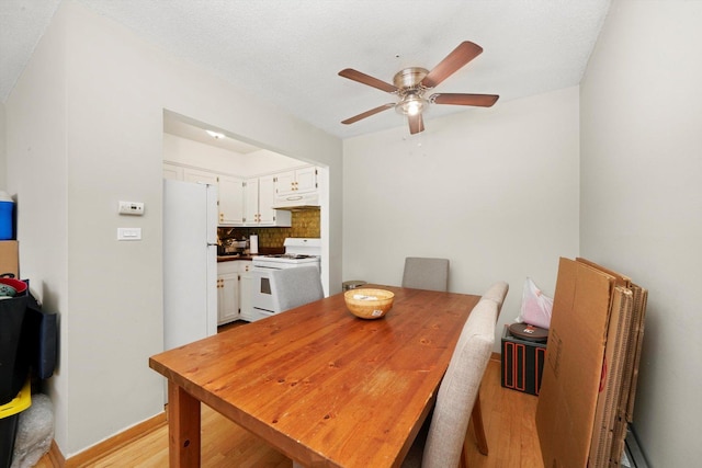 dining room featuring a textured ceiling, light wood-type flooring, and ceiling fan