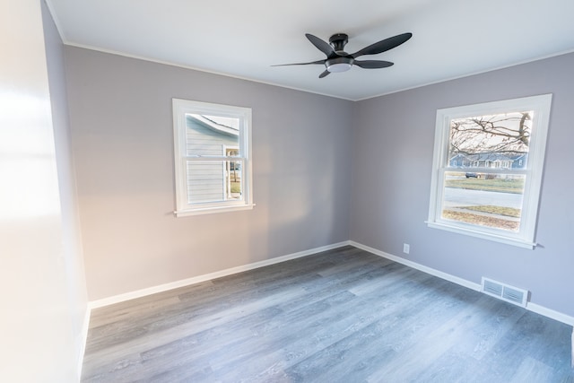 empty room featuring wood-type flooring, a healthy amount of sunlight, and ceiling fan