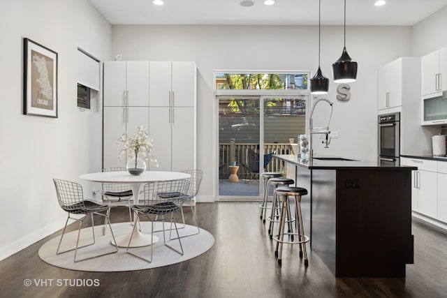 kitchen with decorative light fixtures, white cabinets, sink, and oven