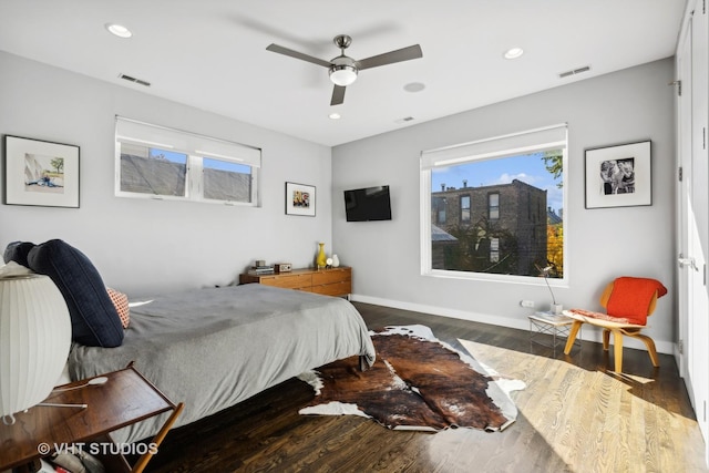 bedroom with ceiling fan, dark wood-type flooring, and multiple windows