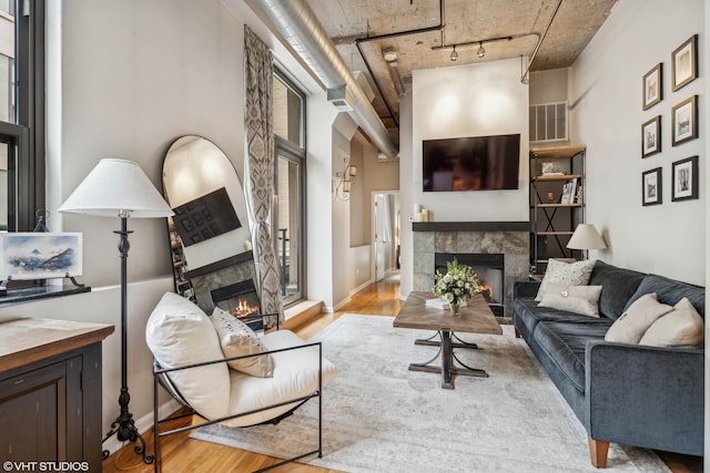 living room with a tile fireplace, track lighting, and light wood-type flooring