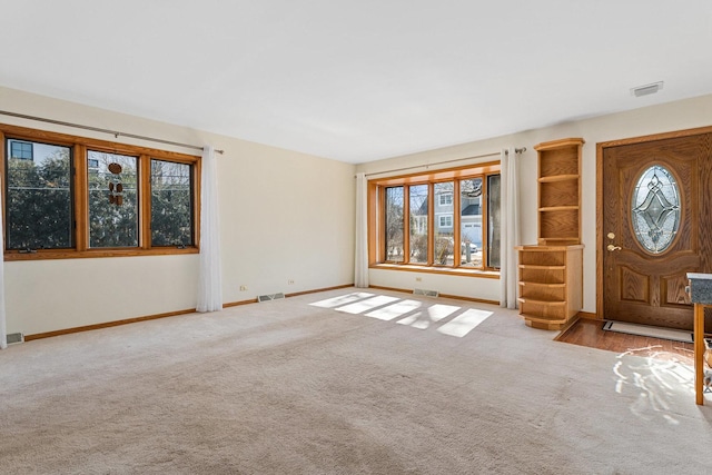 foyer entrance with carpet floors, baseboards, and visible vents