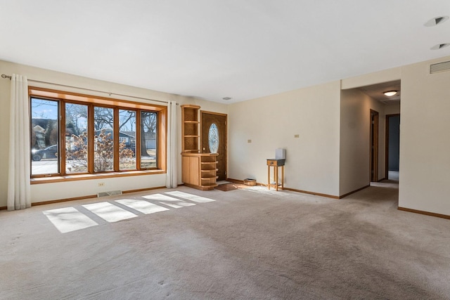 carpeted spare room featuring baseboards and visible vents