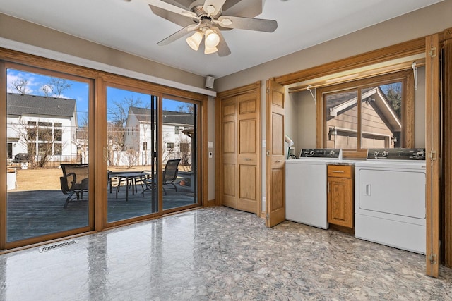 laundry room with a ceiling fan, washing machine and dryer, cabinet space, and visible vents