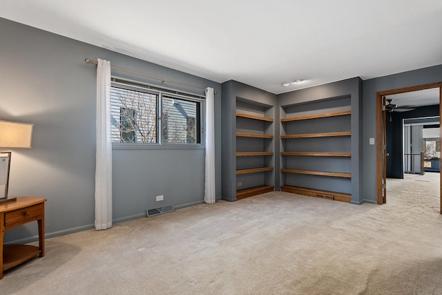 carpeted spare room with baseboards, visible vents, and a ceiling fan