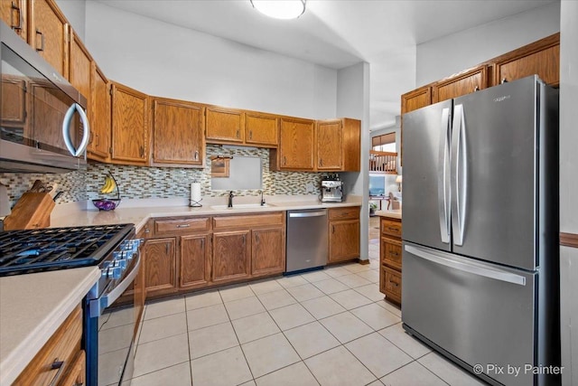 kitchen featuring stainless steel appliances, light tile patterned floors, a high ceiling, backsplash, and sink