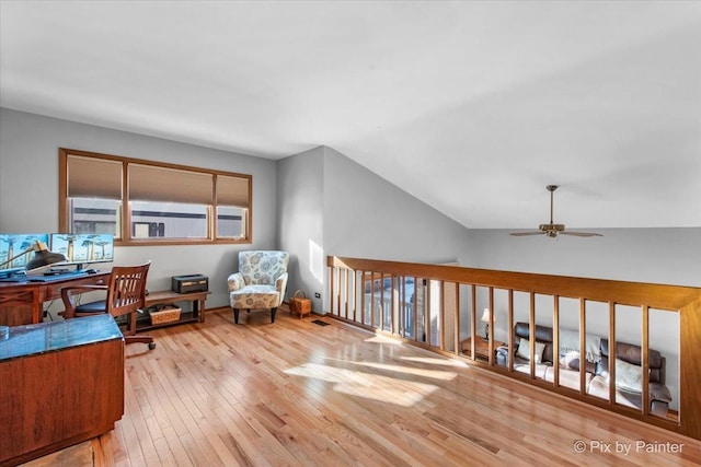 home office with vaulted ceiling, ceiling fan, and light hardwood / wood-style flooring