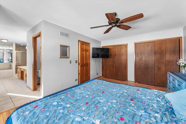 unfurnished bedroom featuring ensuite bath, multiple closets, and ceiling fan