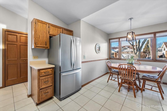 kitchen with a chandelier, hanging light fixtures, light tile patterned floors, stainless steel fridge, and lofted ceiling