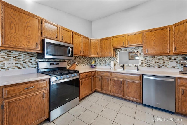 kitchen with appliances with stainless steel finishes, backsplash, sink, and light tile patterned floors