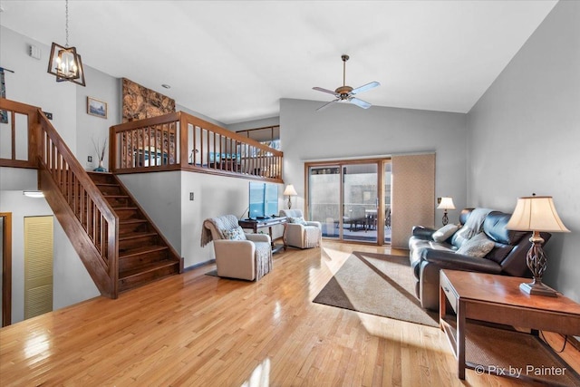 living room featuring light wood-type flooring, high vaulted ceiling, and ceiling fan with notable chandelier