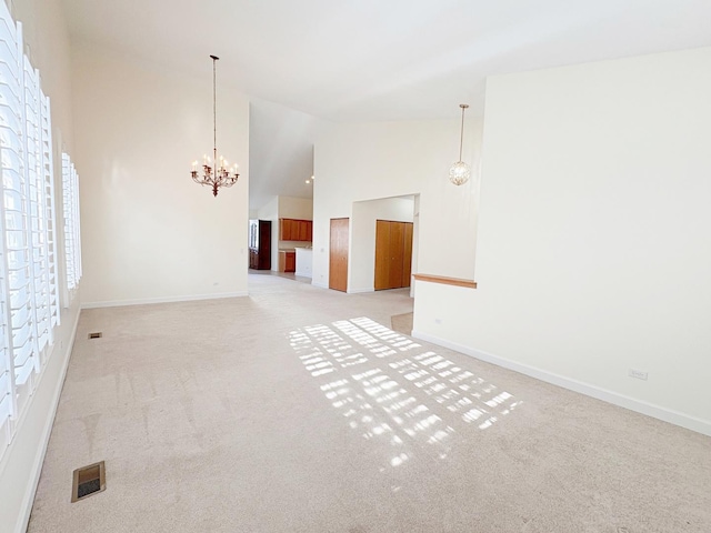 unfurnished room with a chandelier, light carpet, and high vaulted ceiling