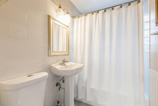 bathroom with sink, toilet, and tile walls