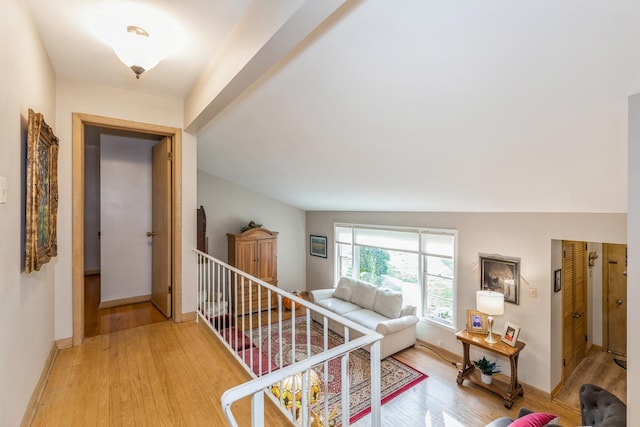 hallway with hardwood / wood-style floors and vaulted ceiling