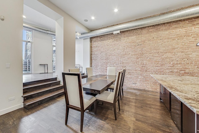 dining room with dark wood-type flooring and brick wall