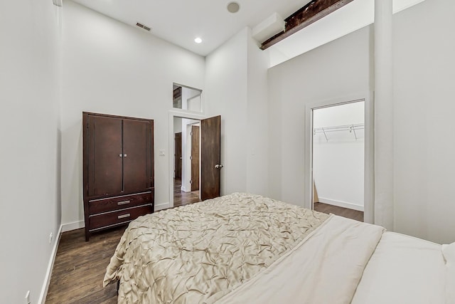 bedroom featuring a spacious closet, a closet, a towering ceiling, and dark hardwood / wood-style floors