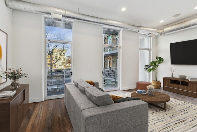 living room featuring expansive windows, hardwood / wood-style floors, a towering ceiling, and a healthy amount of sunlight