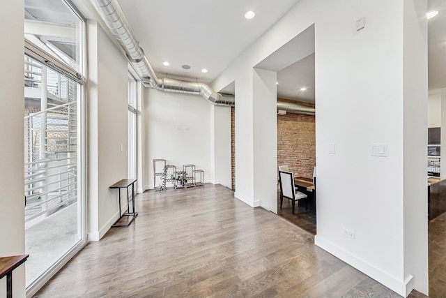 corridor with hardwood / wood-style floors and brick wall