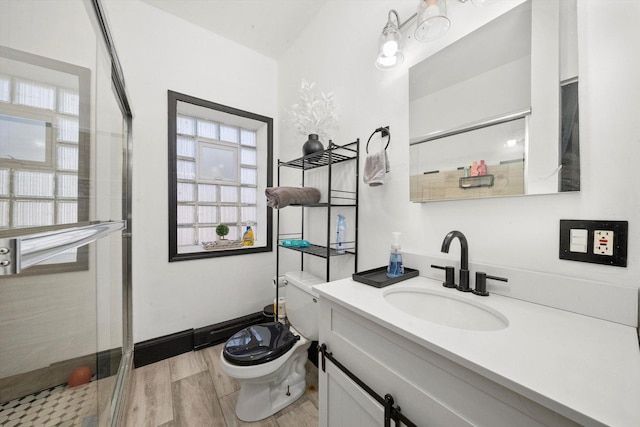 bathroom with a wealth of natural light, vanity, wood-type flooring, and toilet