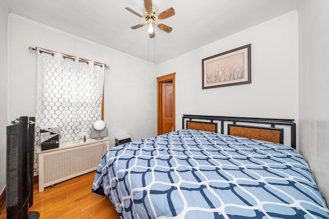 bedroom featuring hardwood / wood-style floors, ceiling fan, radiator heating unit, and crown molding