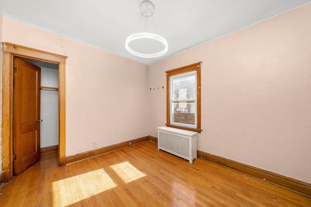 unfurnished bedroom featuring radiator and light wood-type flooring