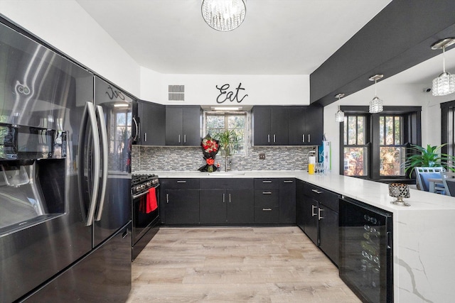 kitchen featuring kitchen peninsula, stainless steel fridge, beverage cooler, black gas stove, and hanging light fixtures