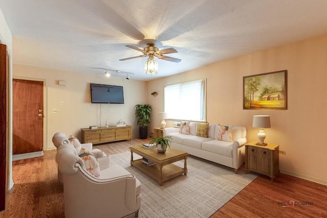 living room featuring hardwood / wood-style flooring, ceiling fan, and a textured ceiling