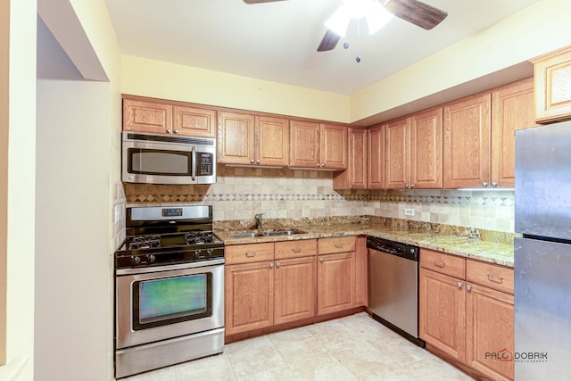 kitchen featuring light stone countertops, sink, ceiling fan, tasteful backsplash, and appliances with stainless steel finishes