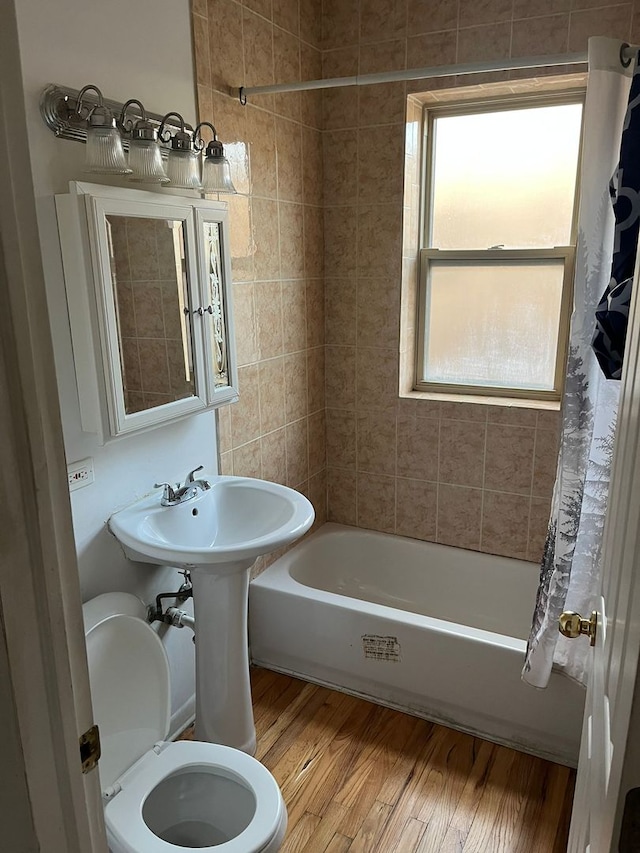 bathroom with toilet, wood-type flooring, and shower / tub combo