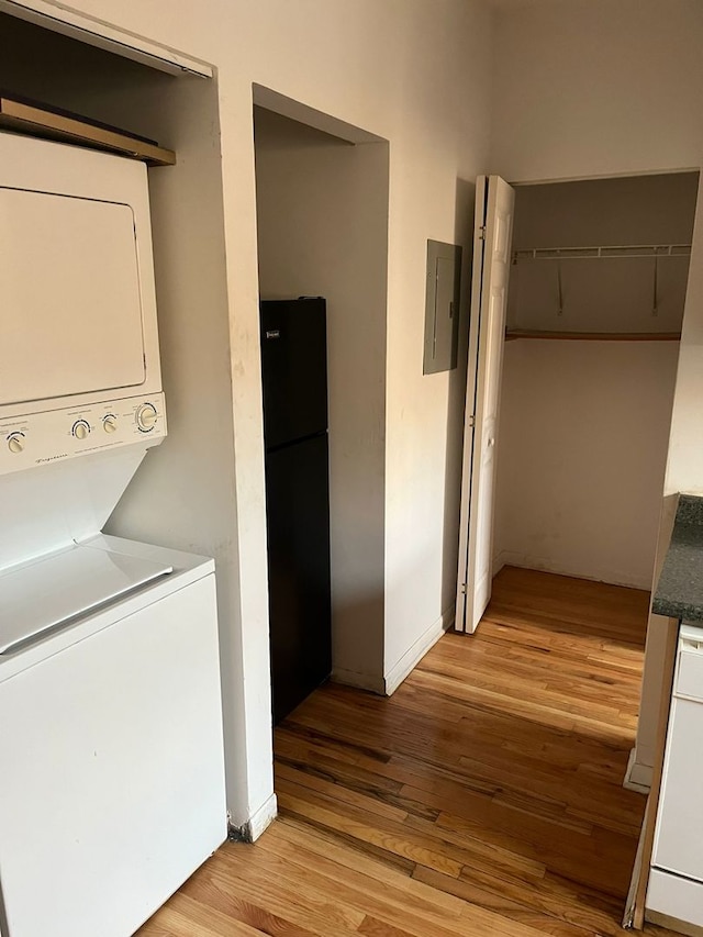 washroom with stacked washer / dryer, electric panel, and light wood-type flooring