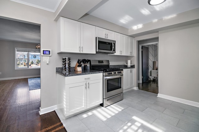 kitchen with dark stone countertops, light hardwood / wood-style floors, white cabinets, and appliances with stainless steel finishes