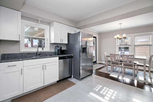 kitchen featuring stainless steel appliances, white cabinetry, plenty of natural light, and sink