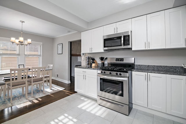 kitchen featuring decorative light fixtures, white cabinets, a chandelier, light tile patterned floors, and stainless steel appliances