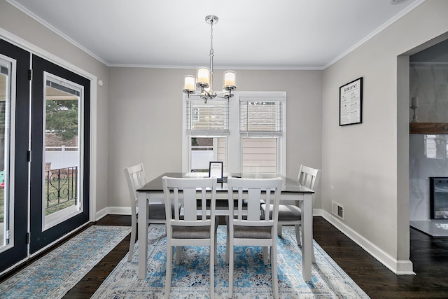 dining room featuring a fireplace, ornamental molding, dark hardwood / wood-style floors, and a notable chandelier