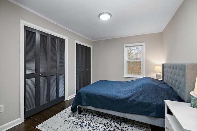 bedroom featuring crown molding, two closets, and dark hardwood / wood-style flooring