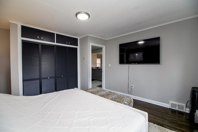 bedroom featuring dark hardwood / wood-style flooring, crown molding, and a closet