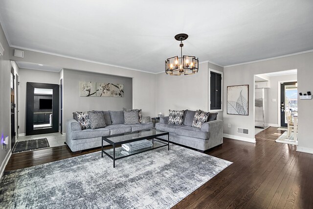 living room featuring crown molding, dark hardwood / wood-style floors, and an inviting chandelier