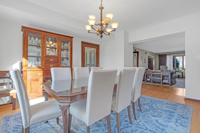 dining space featuring a notable chandelier and light wood-type flooring