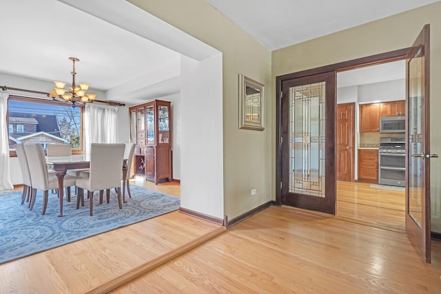 dining area with french doors, a chandelier, and light hardwood / wood-style flooring