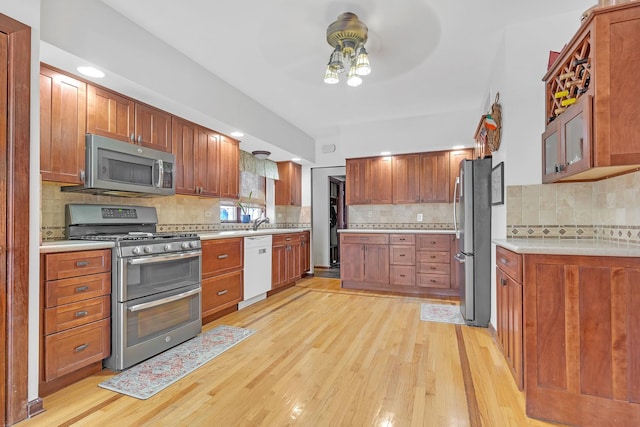 kitchen with appliances with stainless steel finishes, decorative backsplash, and light hardwood / wood-style flooring