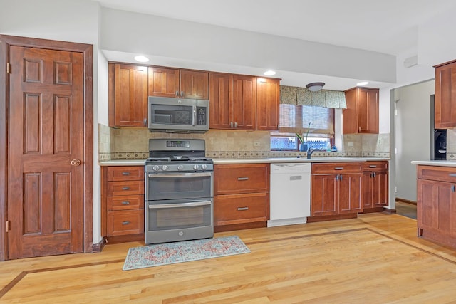 kitchen with light wood-type flooring, stainless steel appliances, and decorative backsplash