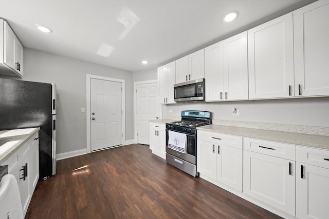 kitchen featuring white cabinetry, dark hardwood / wood-style flooring, light stone counters, and appliances with stainless steel finishes