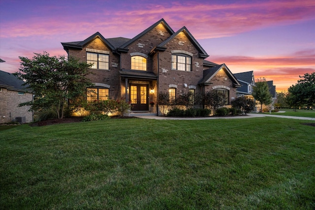 view of front of property with french doors, central air condition unit, and a lawn