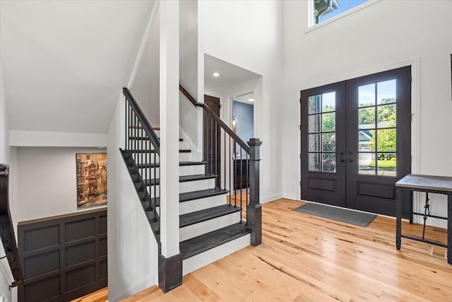 entrance foyer with french doors, a towering ceiling, and wood-type flooring