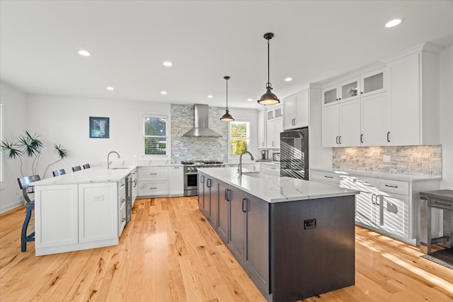 kitchen featuring white cabinets, appliances with stainless steel finishes, a spacious island, and wall chimney exhaust hood