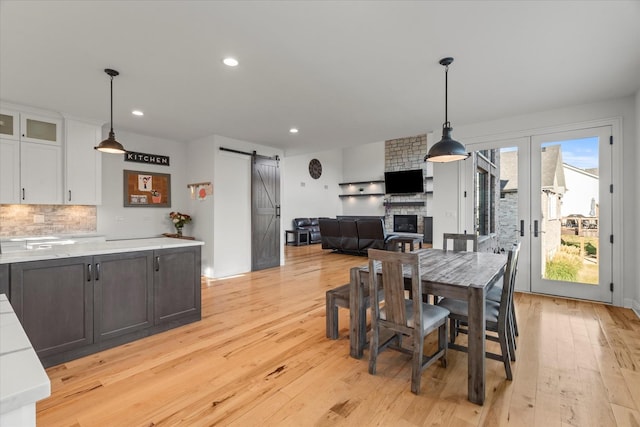 dining space featuring a barn door, light hardwood / wood-style floors, and a fireplace